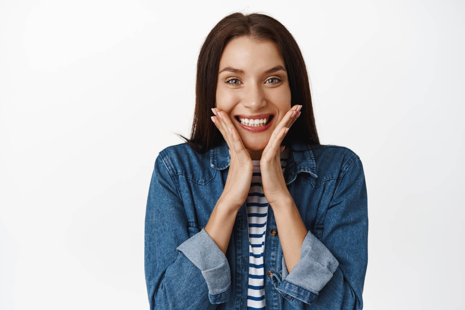 Mulher jovem e sorridente com as mãos no rosto exibe dentes brancos após colocar lentes em resina na Mooca com a AGN Odontologia.