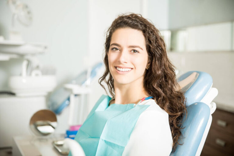 Mulher de cabelos cacheados sorrindo em consultório para tratamentos rápidos de estética dental na Mooca, na AGN Odontologia.