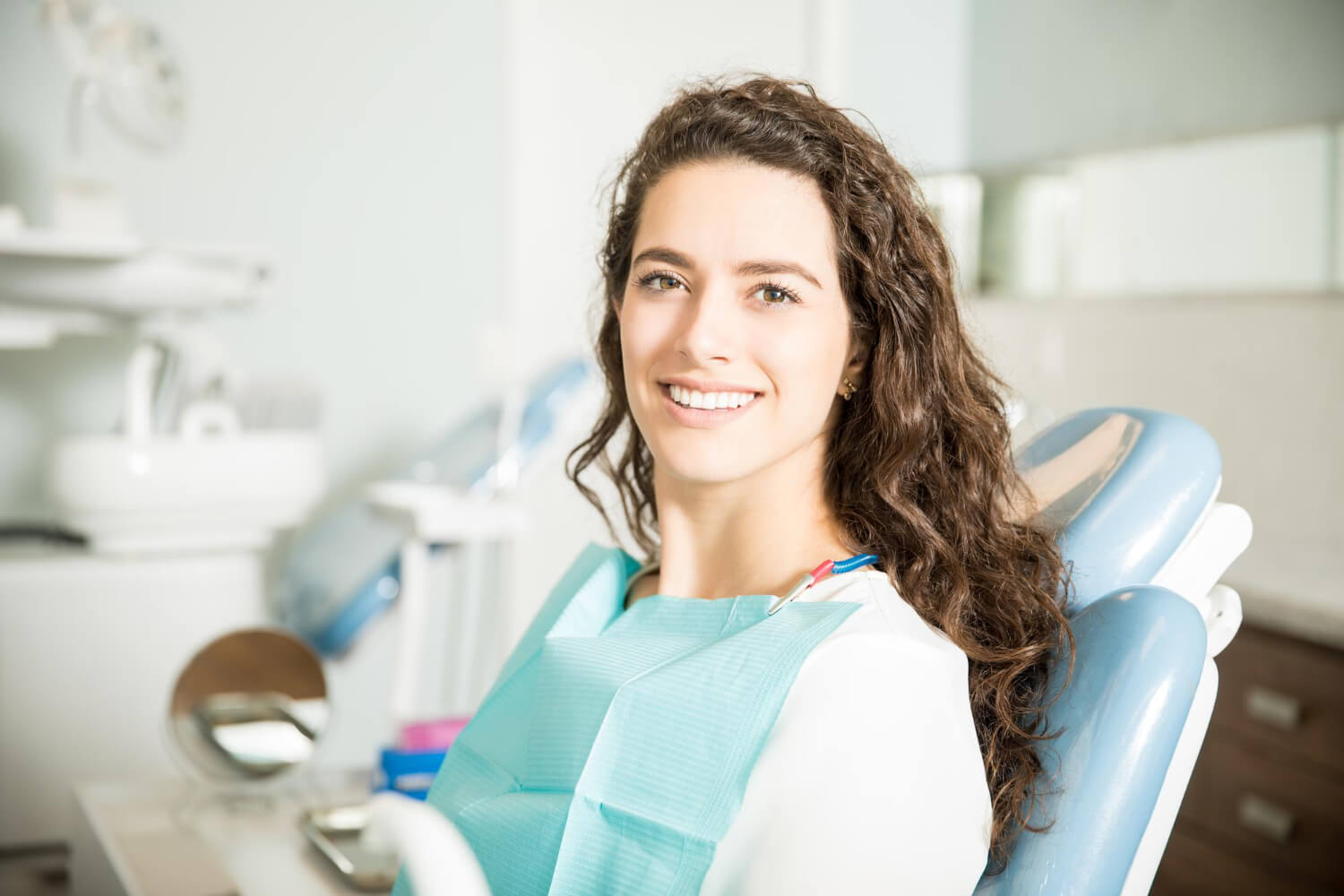 Mulher de cabelos cacheados sorrindo em consultório para tratamentos rápidos de estética dental na Mooca, na AGN Odontologia.